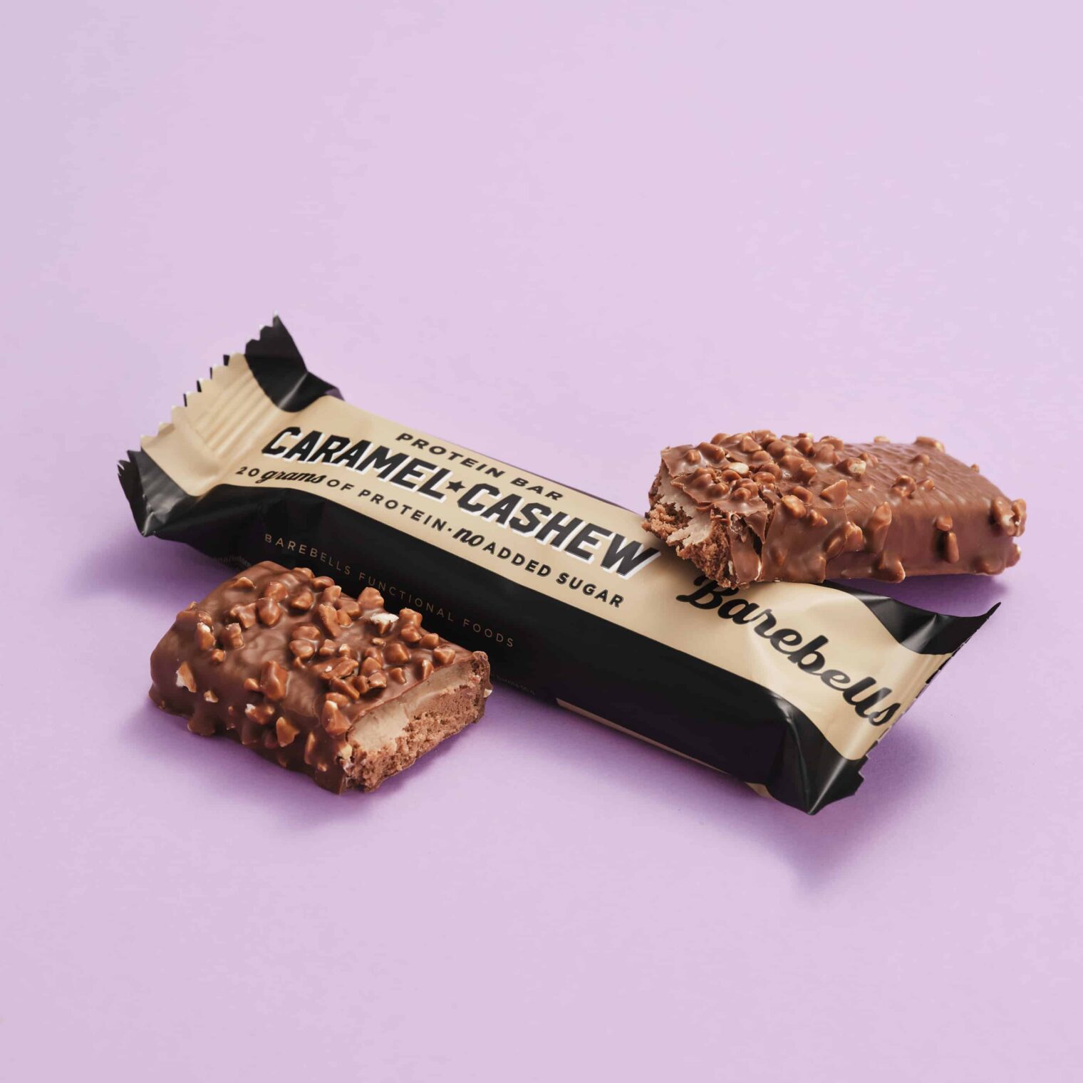Proteinriegel „Caramel Cashew“ halb ausgepackt mit einem angebrochenen Stück daneben.